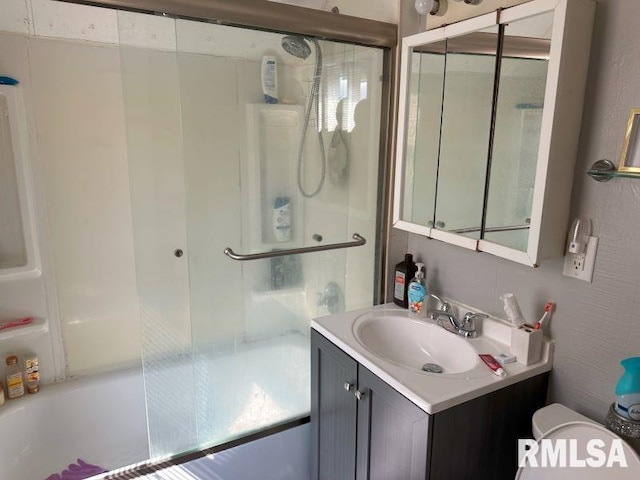 bathroom with toilet, vanity, and bath / shower combo with glass door