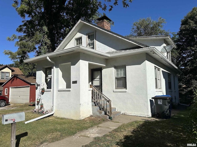 view of front of home with an outdoor structure, a front yard, and a garage