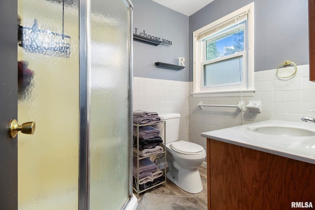 bathroom featuring vanity, toilet, tile walls, and a shower with shower door