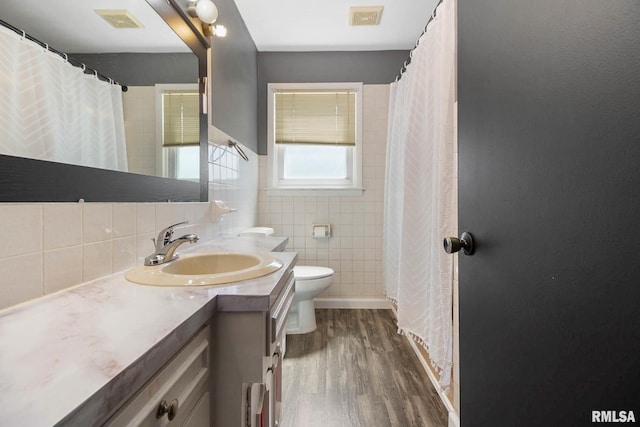 bathroom featuring toilet, vanity, tasteful backsplash, tile walls, and hardwood / wood-style flooring