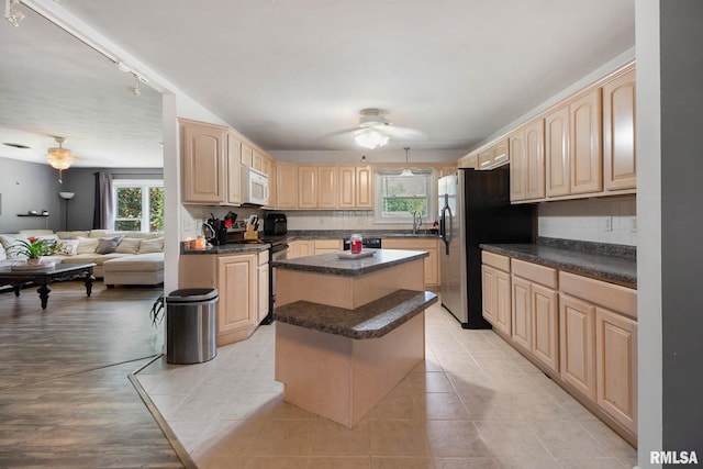 kitchen with a center island, light brown cabinets, light tile patterned flooring, ceiling fan, and decorative backsplash
