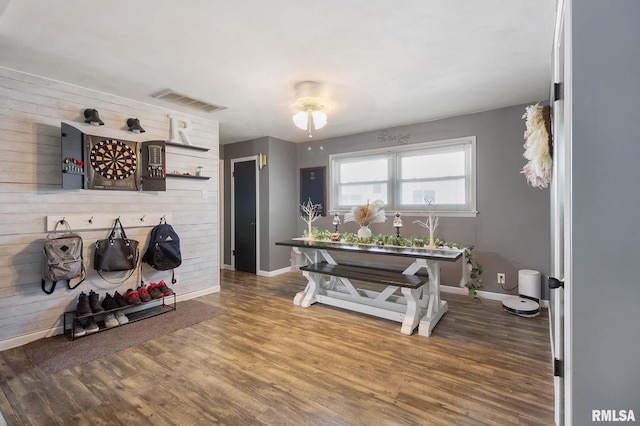 dining room with dark hardwood / wood-style flooring and wooden walls