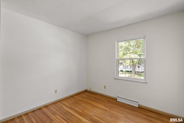 unfurnished room featuring a baseboard heating unit and light hardwood / wood-style floors