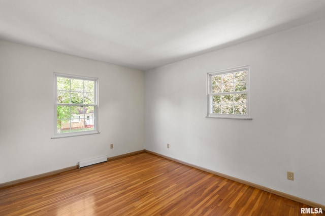 unfurnished room with baseboard heating and light wood-type flooring