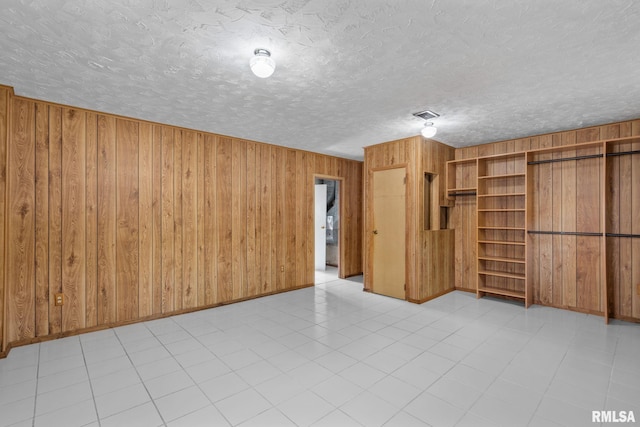 unfurnished room with a textured ceiling and wood walls