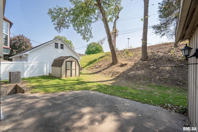 view of yard featuring cooling unit, a storage shed, and a patio area