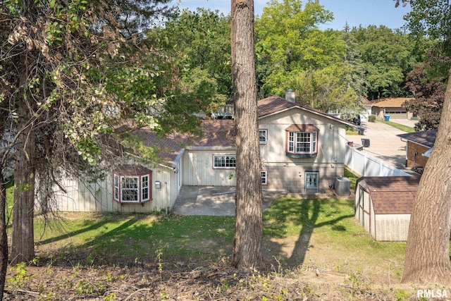 view of front of property featuring central AC, a storage unit, and a front lawn