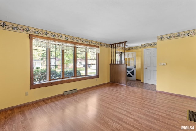 unfurnished room featuring wood-type flooring and a healthy amount of sunlight