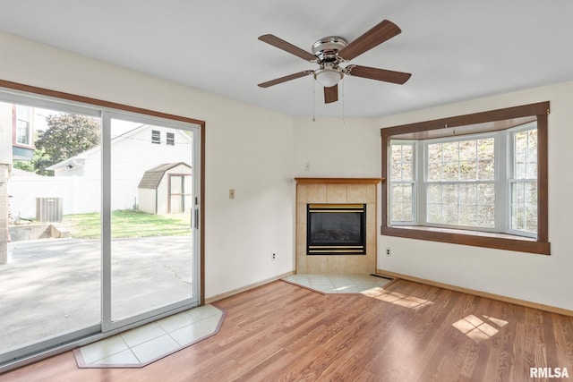 unfurnished living room with light hardwood / wood-style flooring, ceiling fan, and a tile fireplace