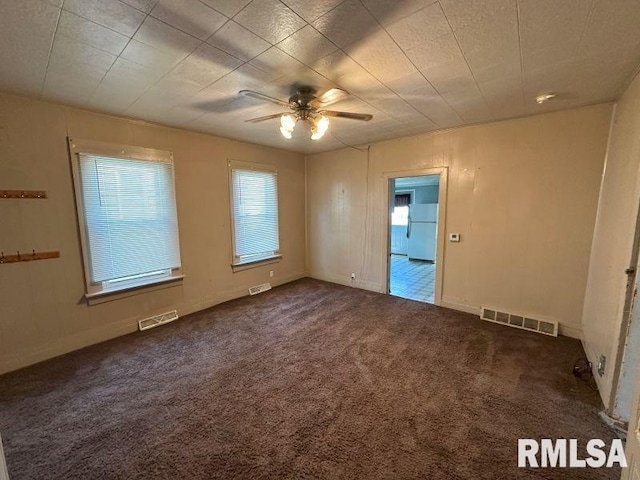 unfurnished room featuring carpet floors, visible vents, and a ceiling fan