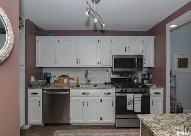 kitchen with light stone counters, white cabinets, sink, backsplash, and appliances with stainless steel finishes