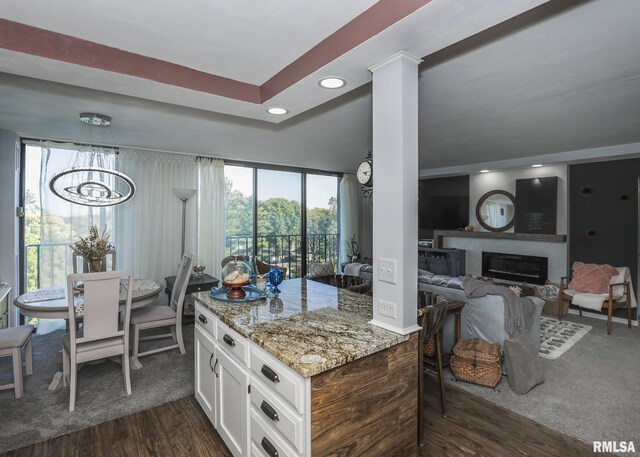 kitchen featuring white cabinets, light stone countertops, plenty of natural light, and a chandelier