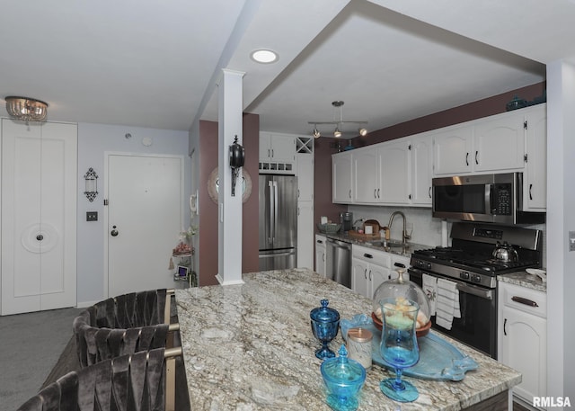 kitchen with white cabinetry, light stone counters, appliances with stainless steel finishes, and a sink