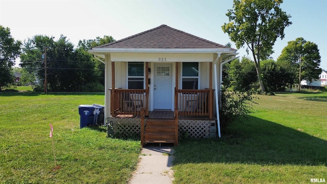 view of front facade with covered porch, a front lawn, and a shingled roof