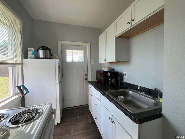 kitchen featuring dark wood finished floors, dark countertops, stove, white cabinetry, and a sink