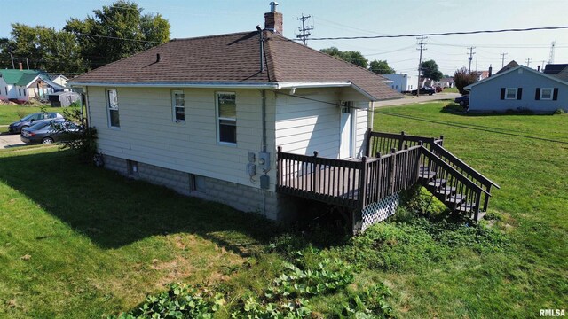 rear view of house featuring roof with shingles, a yard, a chimney, and a wooden deck