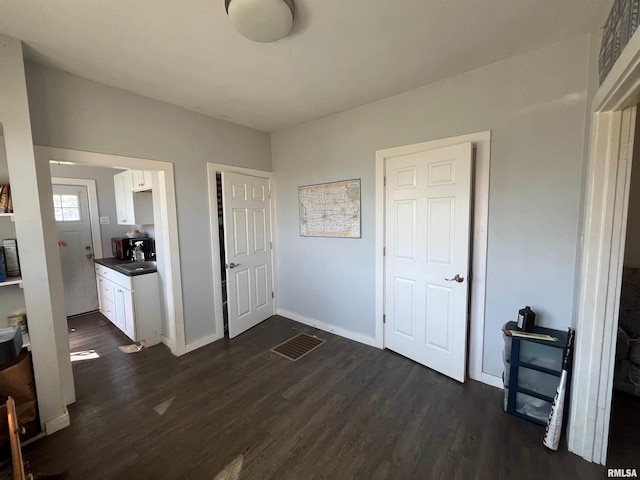 bedroom with dark wood-type flooring, a sink, and baseboards