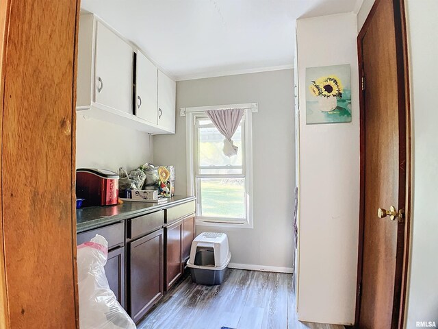 kitchen featuring wood-type flooring, crown molding, dark brown cabinets, and white cabinets