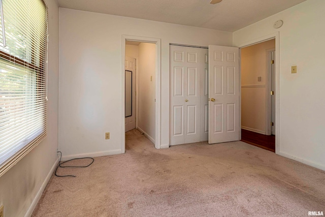 unfurnished bedroom featuring light carpet, a closet, and ceiling fan