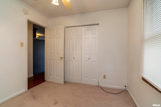 unfurnished bedroom with ceiling fan, a textured ceiling, carpet floors, a closet, and crown molding