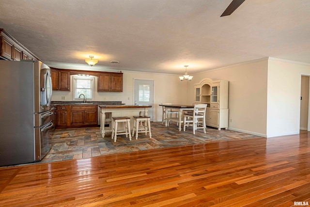 kitchen featuring a kitchen island, dark hardwood / wood-style flooring, a kitchen breakfast bar, stainless steel fridge, and ornamental molding