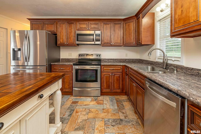 kitchen featuring butcher block counters, appliances with stainless steel finishes, sink, and ornamental molding