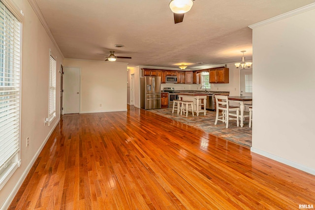 unfurnished living room with ornamental molding, hardwood / wood-style flooring, and ceiling fan with notable chandelier