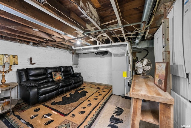 basement featuring electric panel, heating unit, and hardwood / wood-style flooring