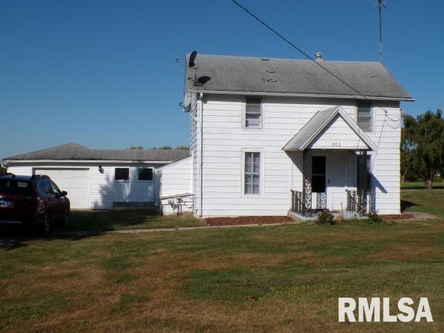 back of property with a garage and a lawn