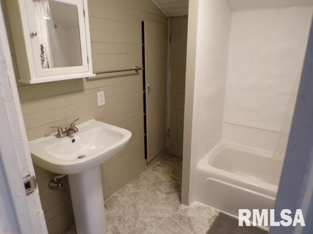 bathroom featuring tile walls and bathing tub / shower combination