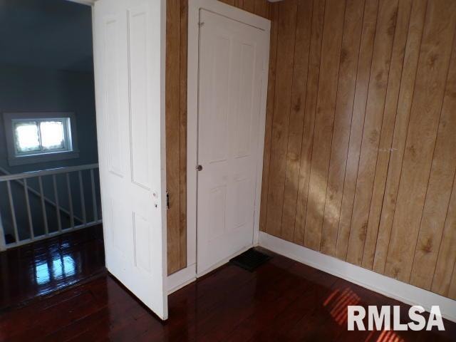 unfurnished bedroom with wooden walls and dark wood-type flooring