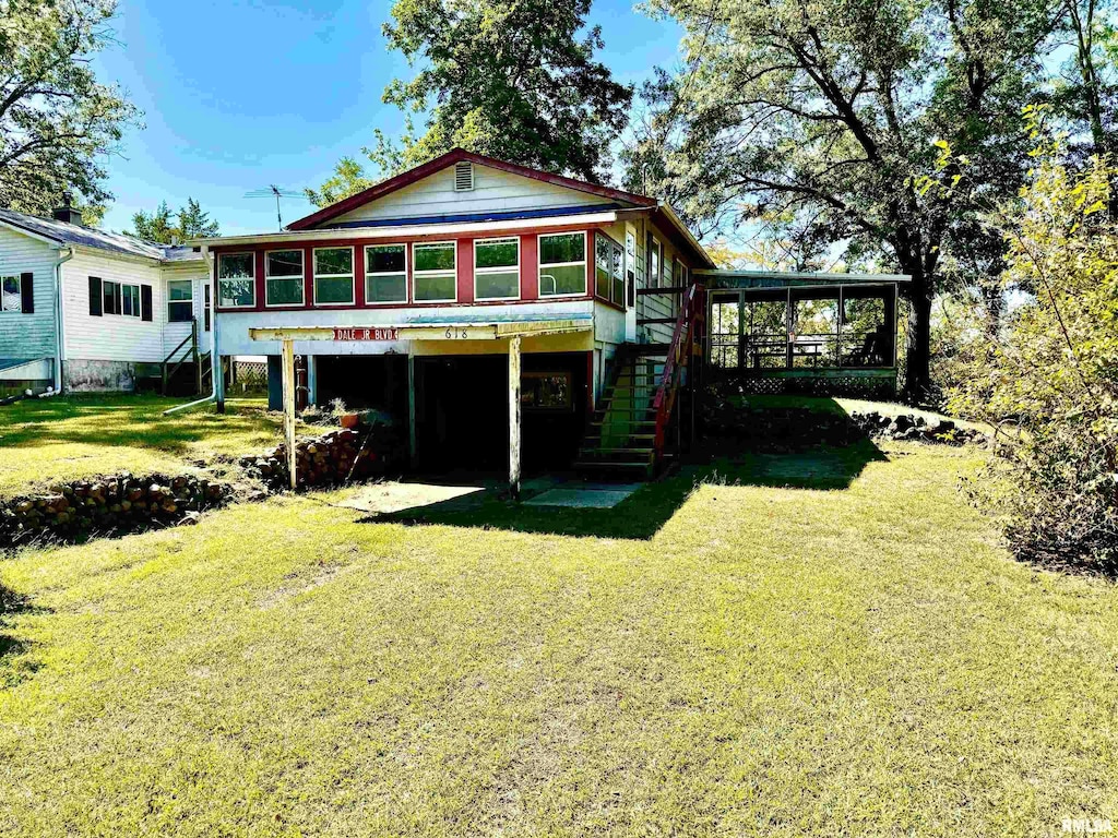 rear view of property featuring a sunroom and a yard