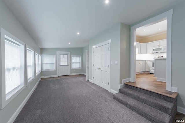 unfurnished living room with light carpet and vaulted ceiling