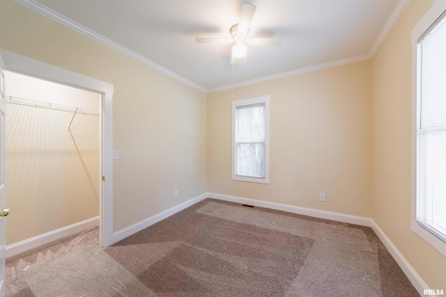 carpeted empty room featuring ceiling fan, ornamental molding, and a wealth of natural light