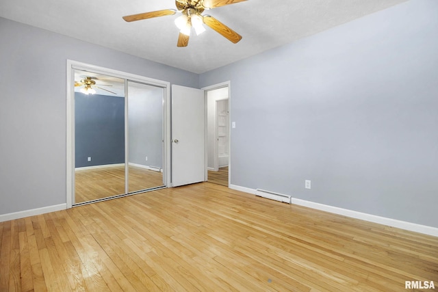 unfurnished bedroom with ceiling fan, a closet, light hardwood / wood-style floors, and a baseboard heating unit