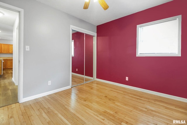 unfurnished bedroom with light hardwood / wood-style floors, ceiling fan, and a closet