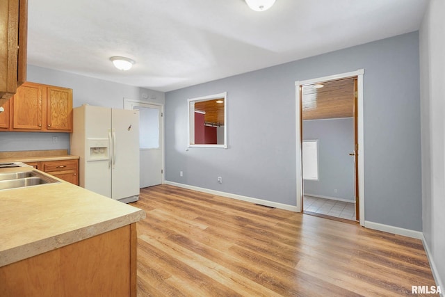 kitchen with light wood-type flooring, white refrigerator with ice dispenser, and sink