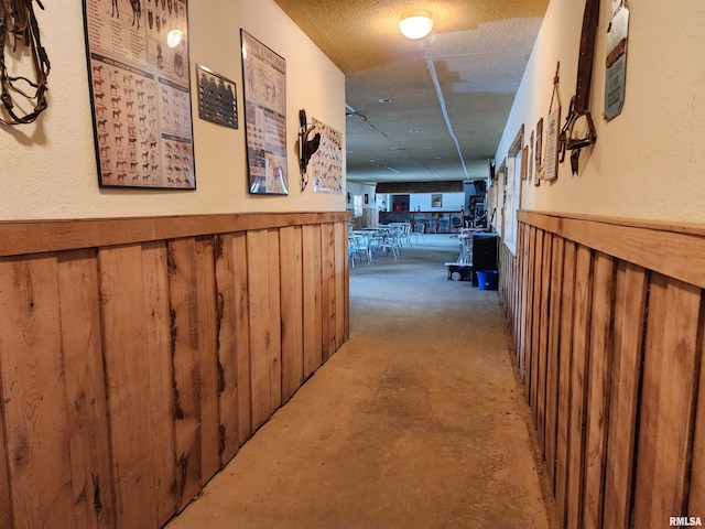 corridor featuring a textured ceiling and wooden walls