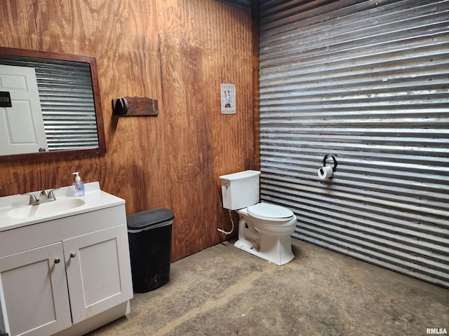 bathroom with wooden walls, vanity, and toilet