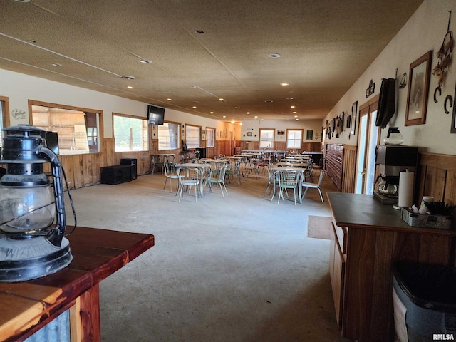 dining area with a textured ceiling, wooden walls, and light carpet