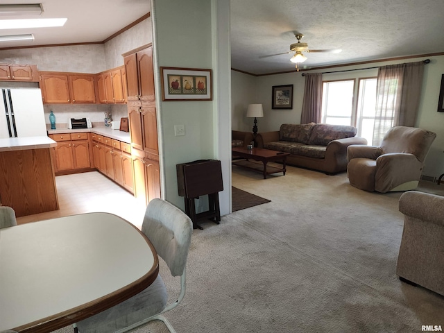 living room with a textured ceiling, ornamental molding, light carpet, and ceiling fan