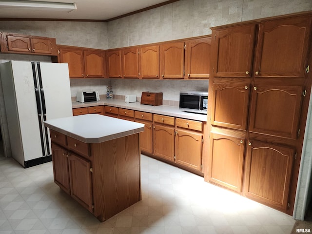 kitchen with ornamental molding, a kitchen island, and white fridge