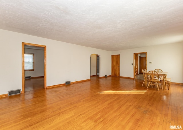 empty room with a textured ceiling and light hardwood / wood-style flooring