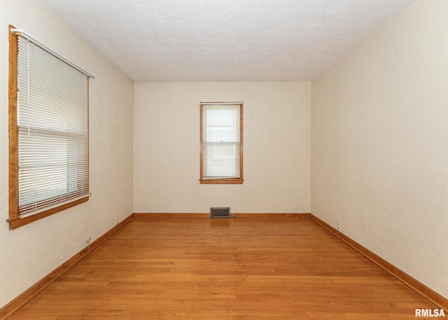 spare room featuring a textured ceiling and light hardwood / wood-style flooring