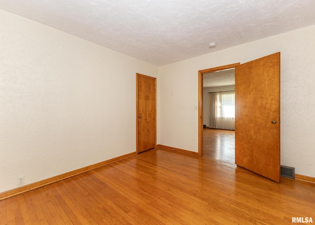 unfurnished room featuring light hardwood / wood-style floors and a textured ceiling