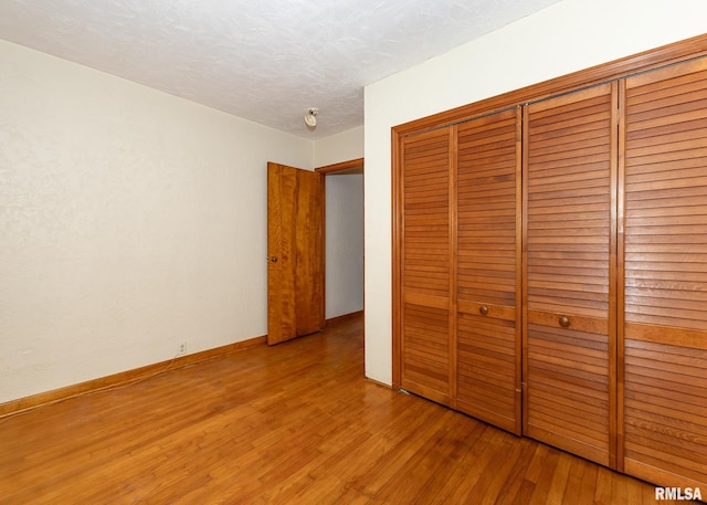 unfurnished bedroom featuring light wood-type flooring, a textured ceiling, and a closet