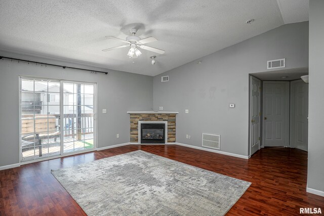 unfurnished living room with a stone fireplace, dark hardwood / wood-style flooring, a textured ceiling, lofted ceiling, and ceiling fan