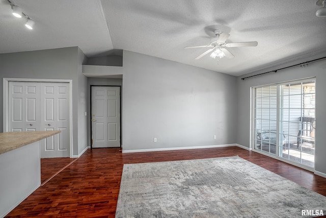 unfurnished room featuring ceiling fan, a textured ceiling, dark hardwood / wood-style floors, and vaulted ceiling