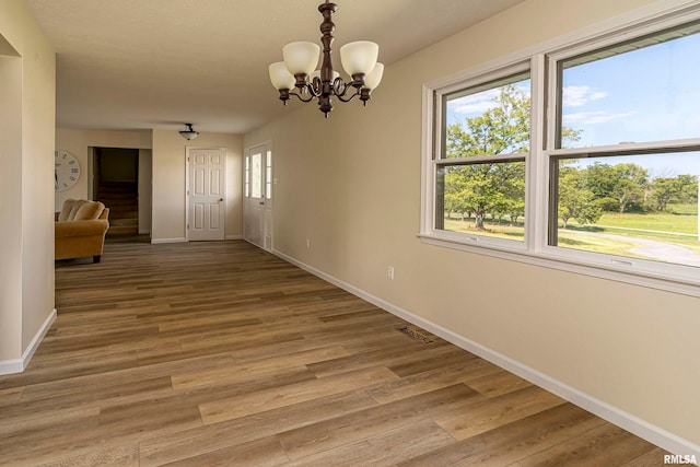 unfurnished dining area with an inviting chandelier and hardwood / wood-style flooring