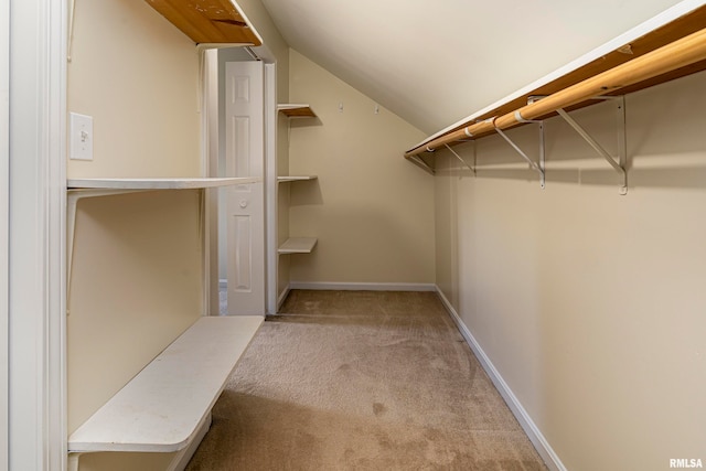 walk in closet with light carpet and vaulted ceiling